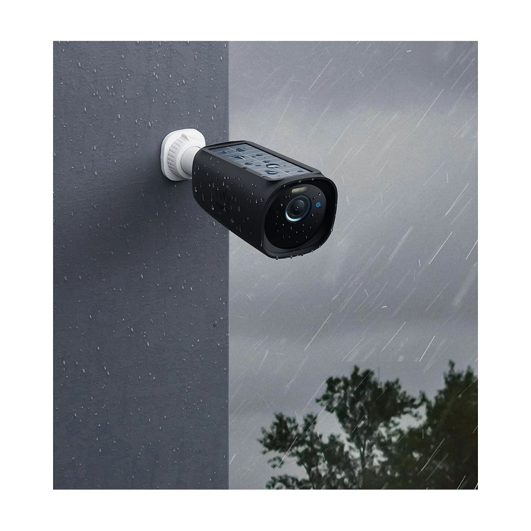 Zwarte EufyCam 3 beschermhoes in de regen, gemonteerd op een muur voor discrete en weerbestendige bewaking.